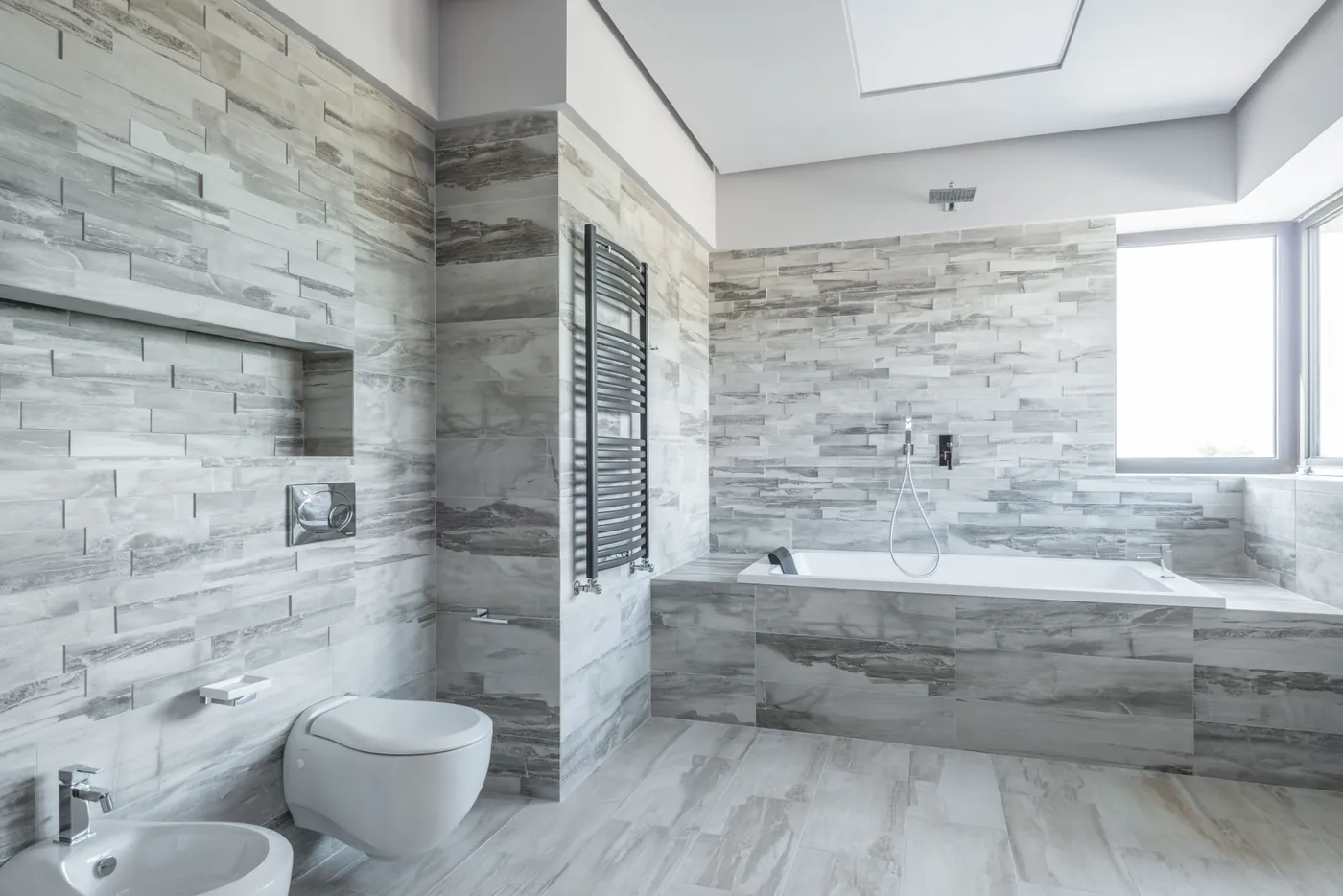 Finished grey tiled bathroom with bath and shower